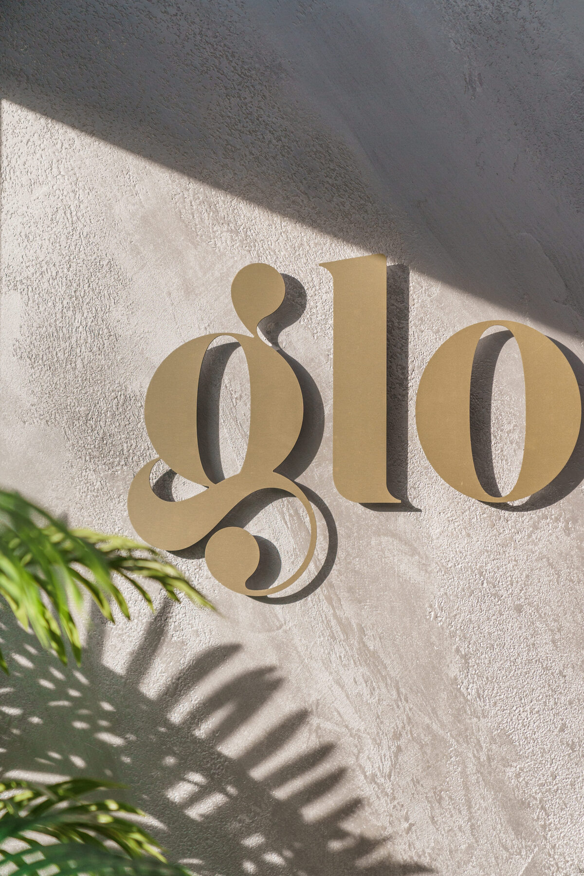 Gouden 'glo'-letters op de betonmuur van de salon